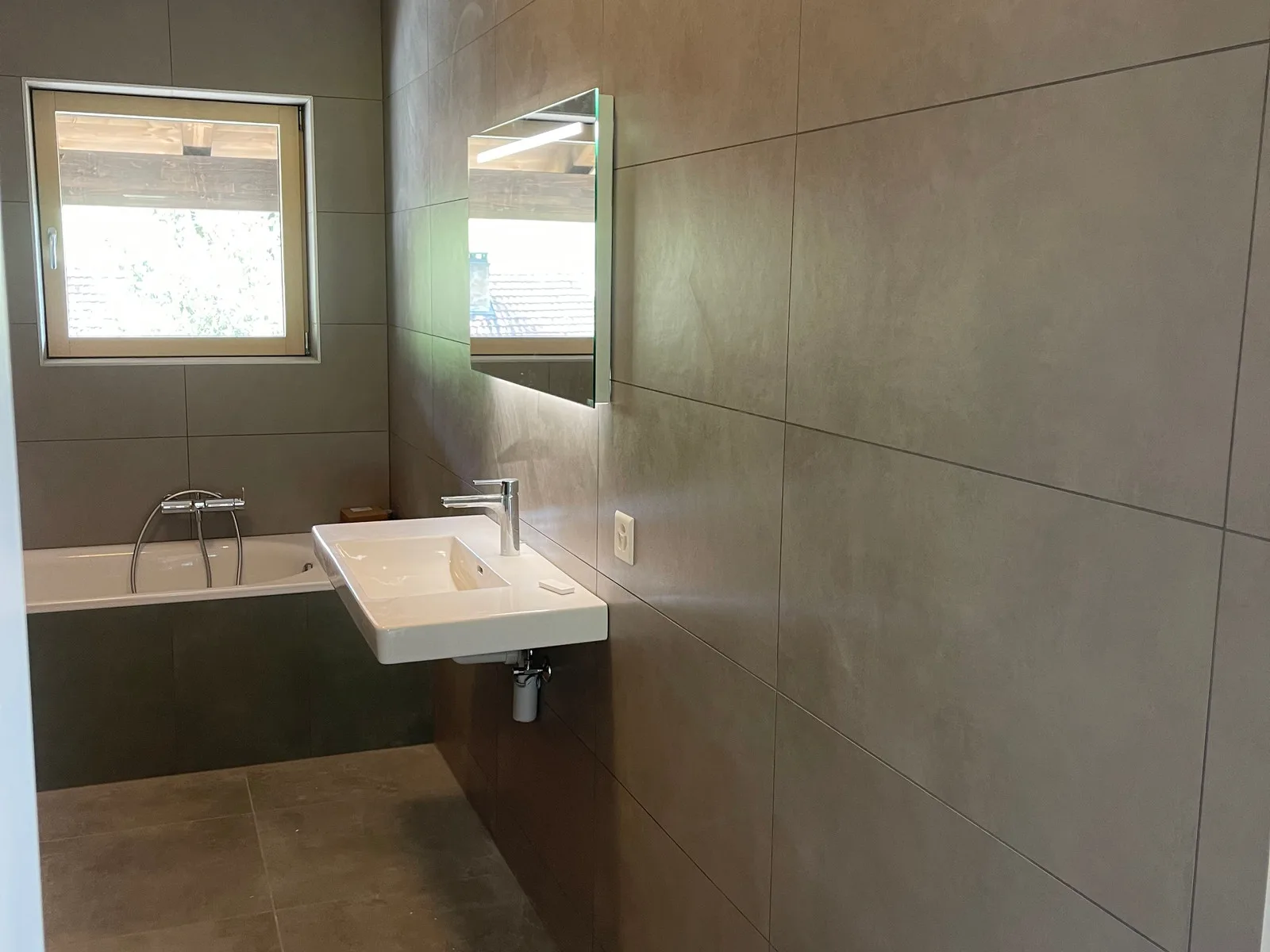 Salle de bains rénovée : baignoire, lavabo suspendu, murs et sol en grès cérame effet pierre naturelle